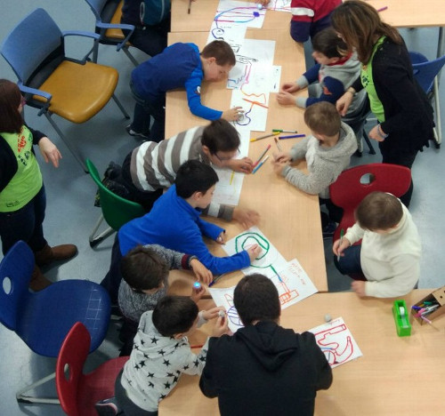 imagen de varios niños en una mesa dibujando con una profesora