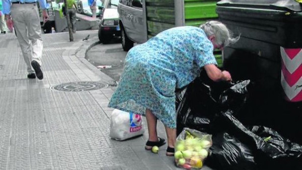 Foto de una señora mayor buscando en la basura