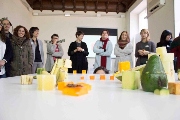 un grupo de personas ante una mesa con figuras hechas con fruta