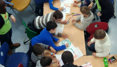 imagen de varios niños en una mesa dibujando con una profesora