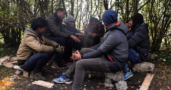 imagen de un grupo de inmigrantes calentándose en un fuego en Calais 