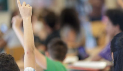 imagen de la mano alzada de un alumno/a en una clase