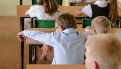 imagen de un niño rubio con gafas en una mesa de clase