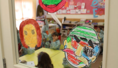 imagen de dibujos infantiles pegados en un espejo de un aula