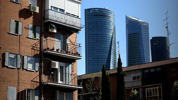 imagen de contraste entre un bloque de pisos del distrito de Fuencarral y las lujosas 4 Torres