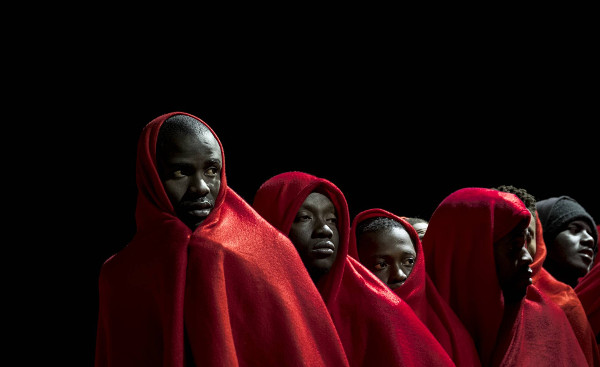imagen de un grupo de inmigrantes de color tapados con mantas rojas