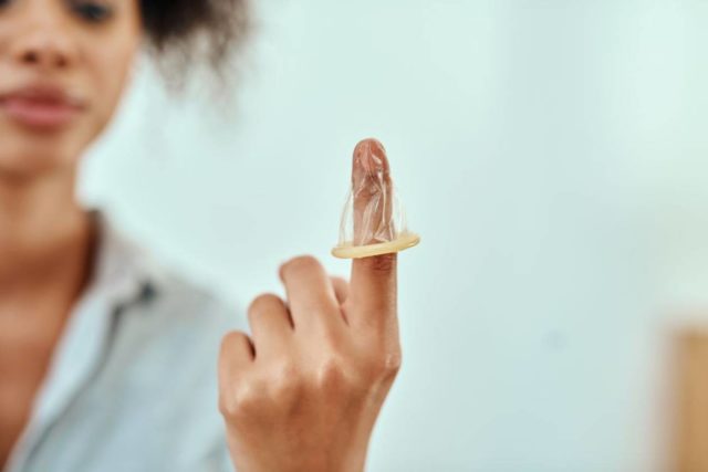 imagen de una joven con un preservativo en la mano