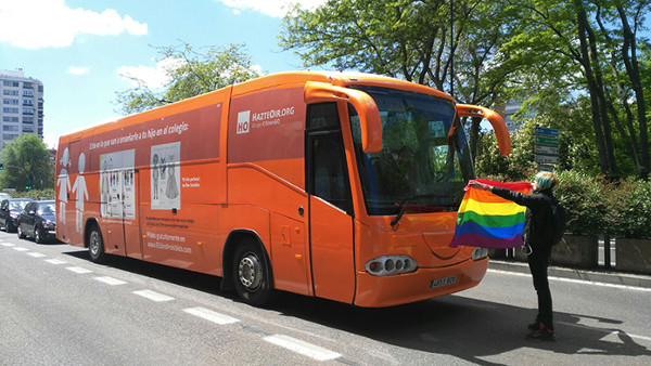 Imagen de una activista con una bandera arcoiris delante del Bus de Hazte Oir