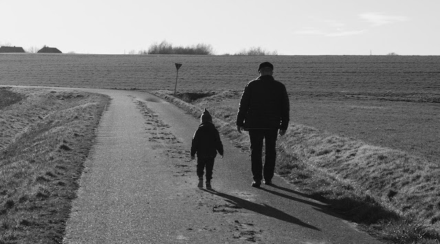Imagen de un anciano y un niño andando por un camino de tierra