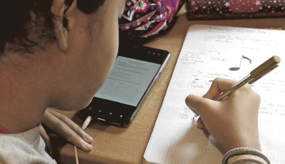 un niño con un smartphone escribe en un cuaderno