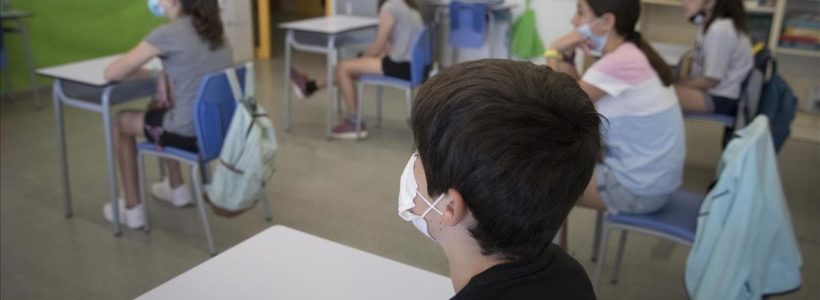 un grupo de niños y niñas asiste a clase con mascarilla