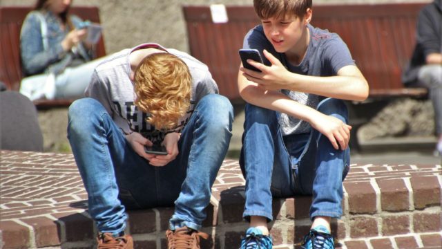 dos adolescentes mirando sus móviles