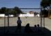 varios niños con mascarilla en un campo de fútbol escolar