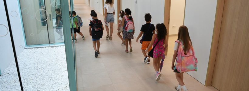 une profesora acompaña a varios alumnos por un pasillo