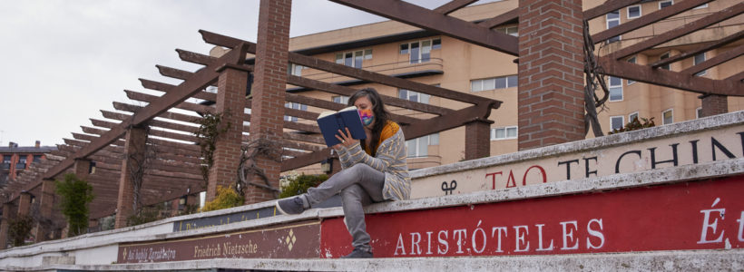 una joven lee un libro en una escalera con escalones como libros de filosofos